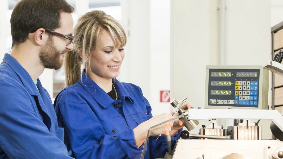 Zwei Studierende wenden ihr erlerntes Fachwissen praktisch an einer Fräsmaschine an. Mithilfe einer Schiebelehre wird die Maßhaltigkeit des hergestellten Zylinders gemessen.