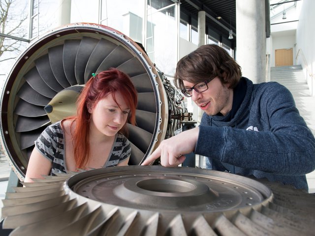 Eine Studentin und ein Student diskutieren an einem Flukzeugtriebwerk miteinander. Foto: Sebastian Rau, BTU