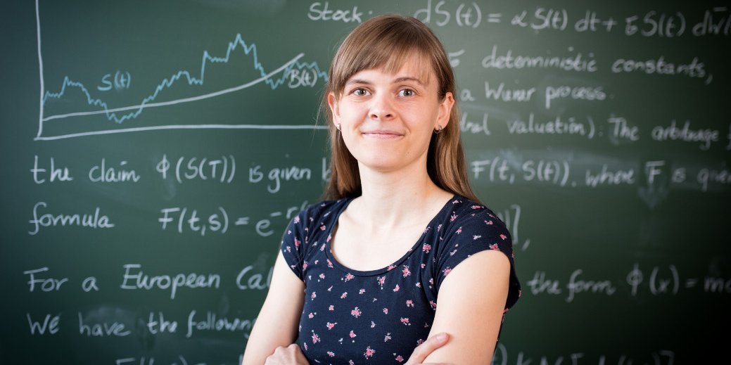 Studentin der Wirtschaftsmathematik vor Tafel mit Graphen und mathematischen Formeln