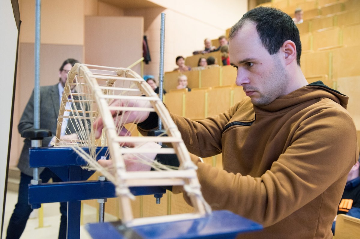 Ein Teilnehmer am Brückenbauwettbewerb positioniert sein Brückenmodell im Prüfstand.