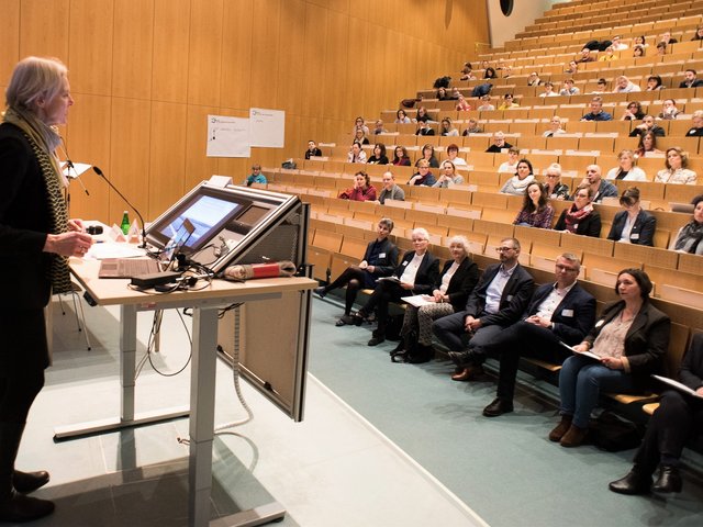 Die BTU-Vizepräsidentin Prof. Dr. Katrin Salchert spricht, am Rednerpult stehend, zu den Teilnehmenden, die im Hörsaal sitzen..