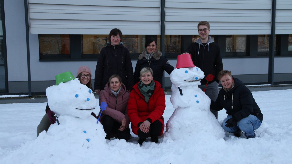 Es ist die Arbeitsgruppe Maltzahn gezeigt mit zwei Schneemännern vor dem Gebäude 15 in Senftenberg. AG Maltzahn 2023 (von links nach rechts): Karolina Majchrzak, Katja Hönzke, Antje Muschter, Christiane Geithe, Anja Michelfeit, Erik Hentschel, Julia von Maltzahn