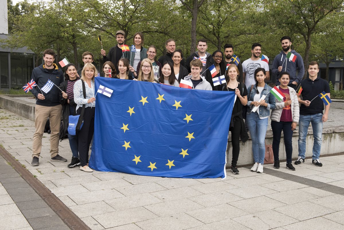 Students with Europe flag in front of cherry grove 