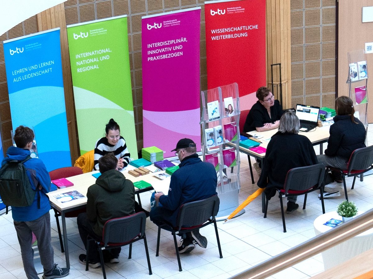 Studienberatererinnen und Studieninterssierte an Tischen sitzend, im Gespräch.