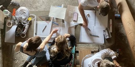 Studierende vor Tisch mit Zeichenmaterial