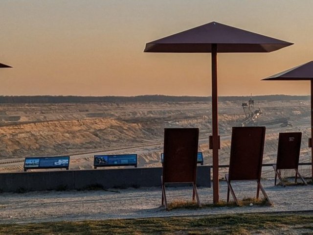 Umbrellas and deck chairs in front of open pit mine panorama