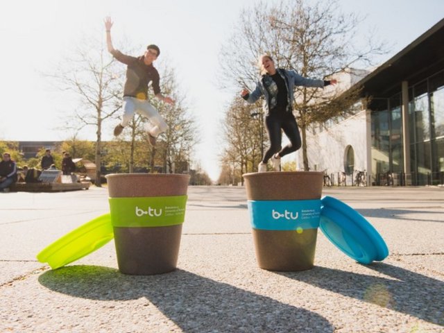 Kaffebecher und Studierende auf dem Zentralcampus