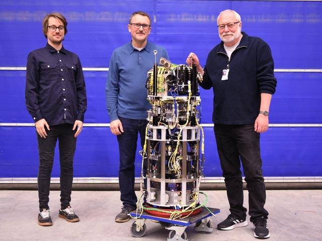 Scientists Dr. Antoine Meyer, Dr.-Ing. Vasyl Motuz and Dr.-Ing. Martin Meier (from left to right) next to the open experiment module in the payload integration hall. 