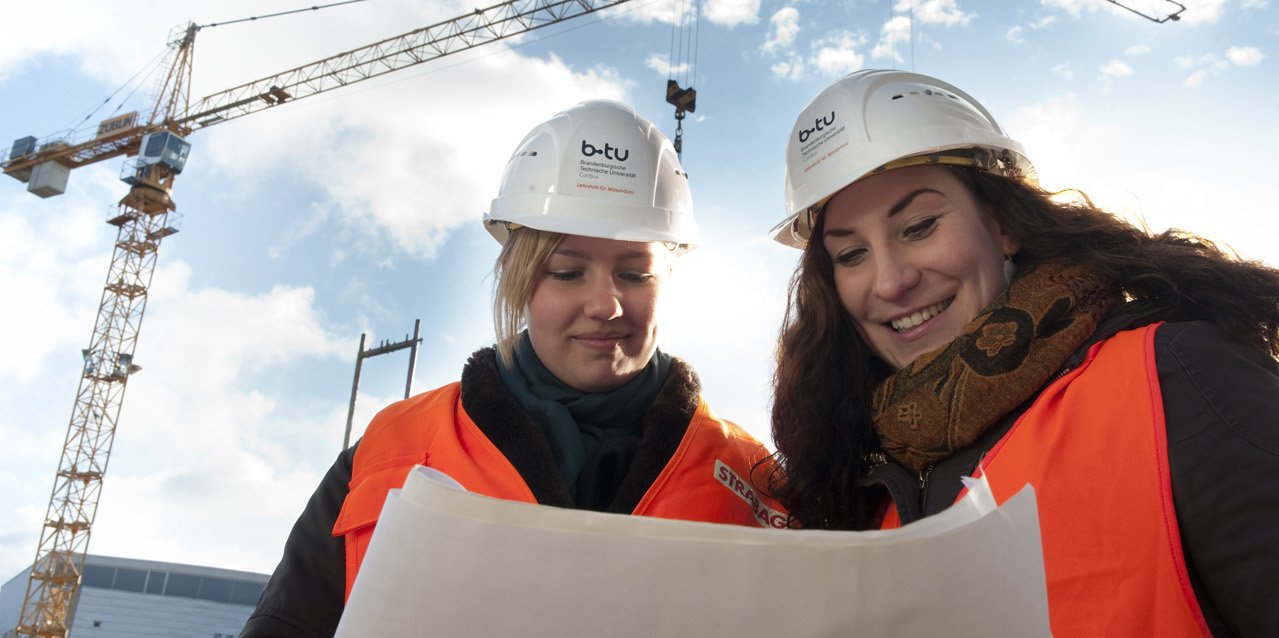 Studentinnen im Master-Studiengang Bauingenieurwesen lesen Baupläne auf der Baustelle