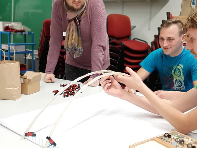 Studierende beim Bau einer Brücke aus Eisstielen und Leim