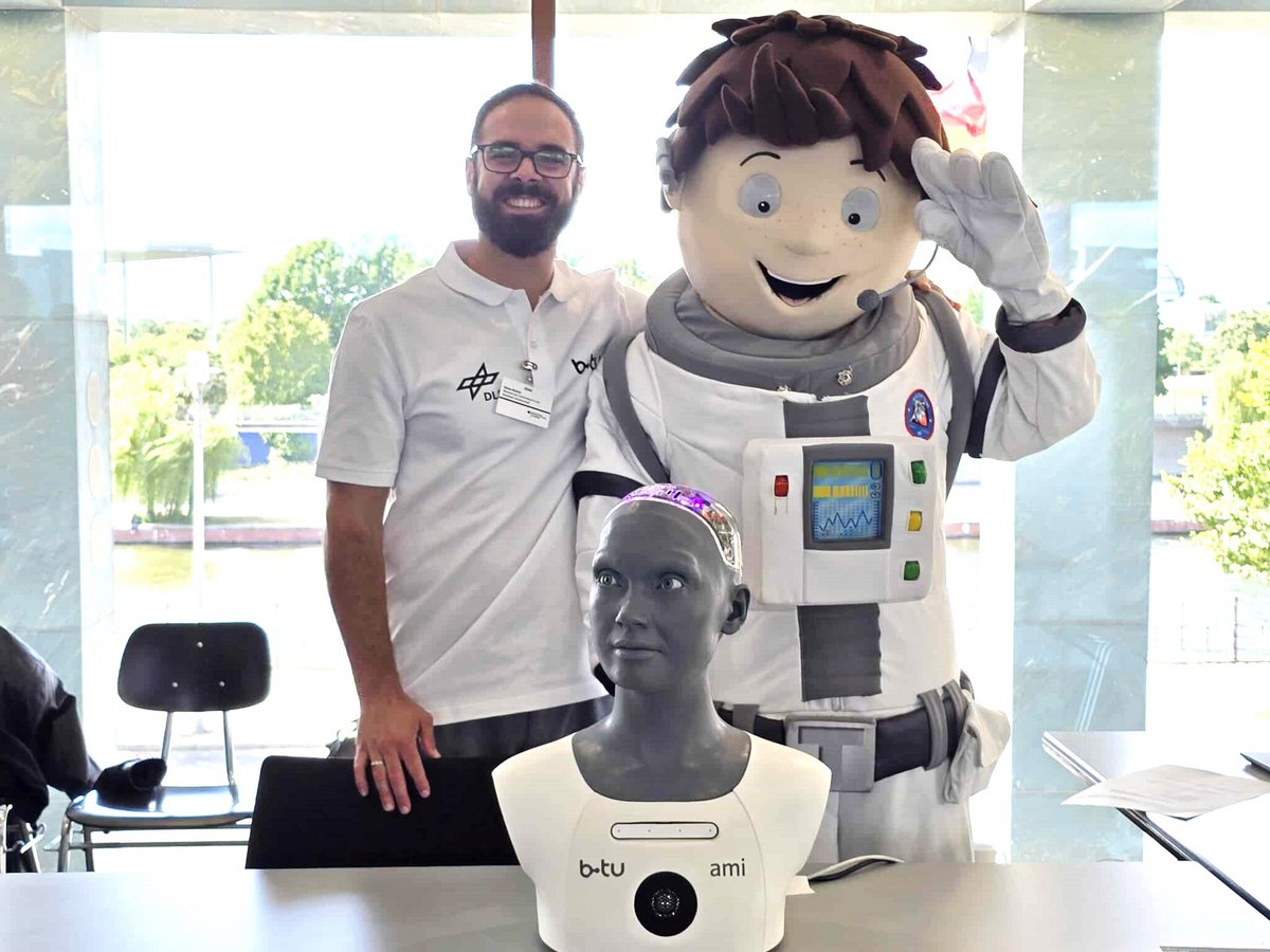 Stefan Richer, Leiter des DLR_School_Labs an der BTU, steht neben dem Maskottchen der Veranstaltung, im Vordergrund der humanoide Roboter Ami. 