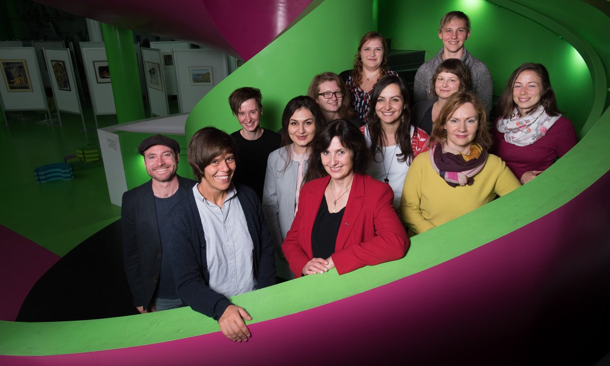 Group of twelve people, part of the team of the MIKOWA research platform, standing on the staircase of the university's library