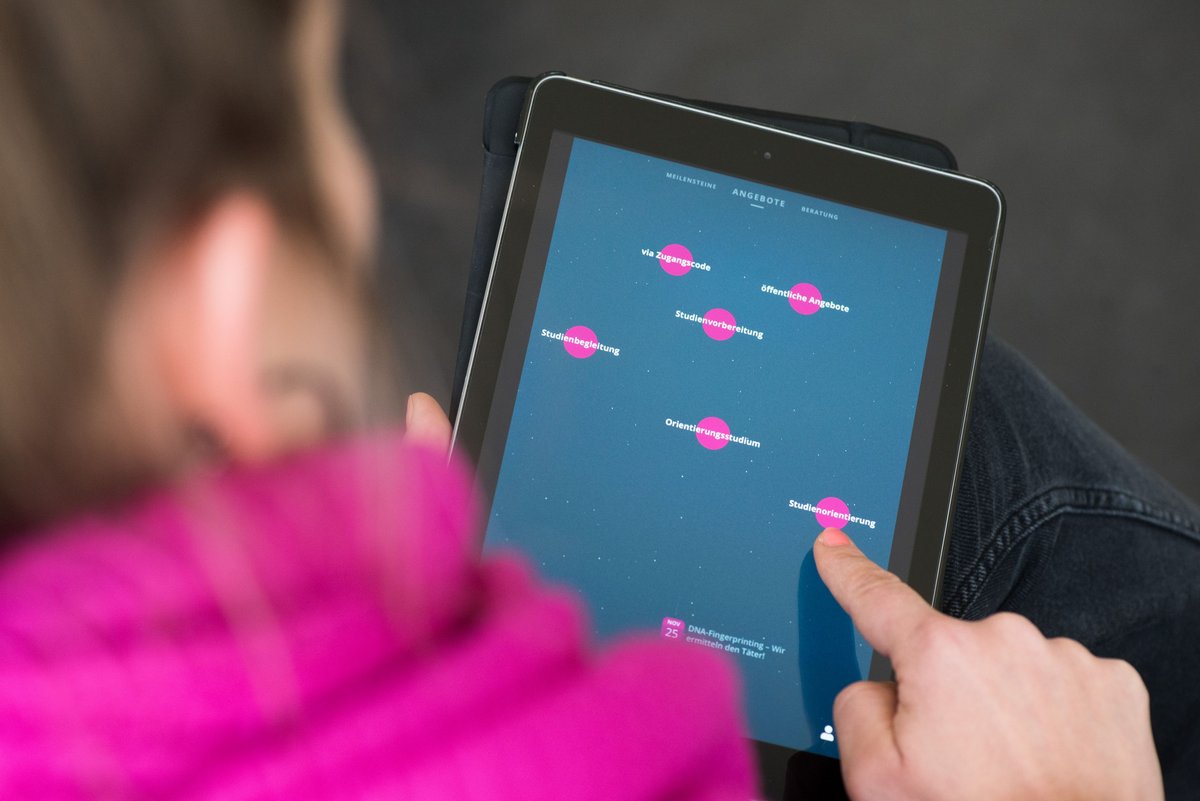 Eine weibliche Person betrachtet die auf einem Tablet abgebildete Benutzeroberfäche der Online-Plattform „EDUpilot“.