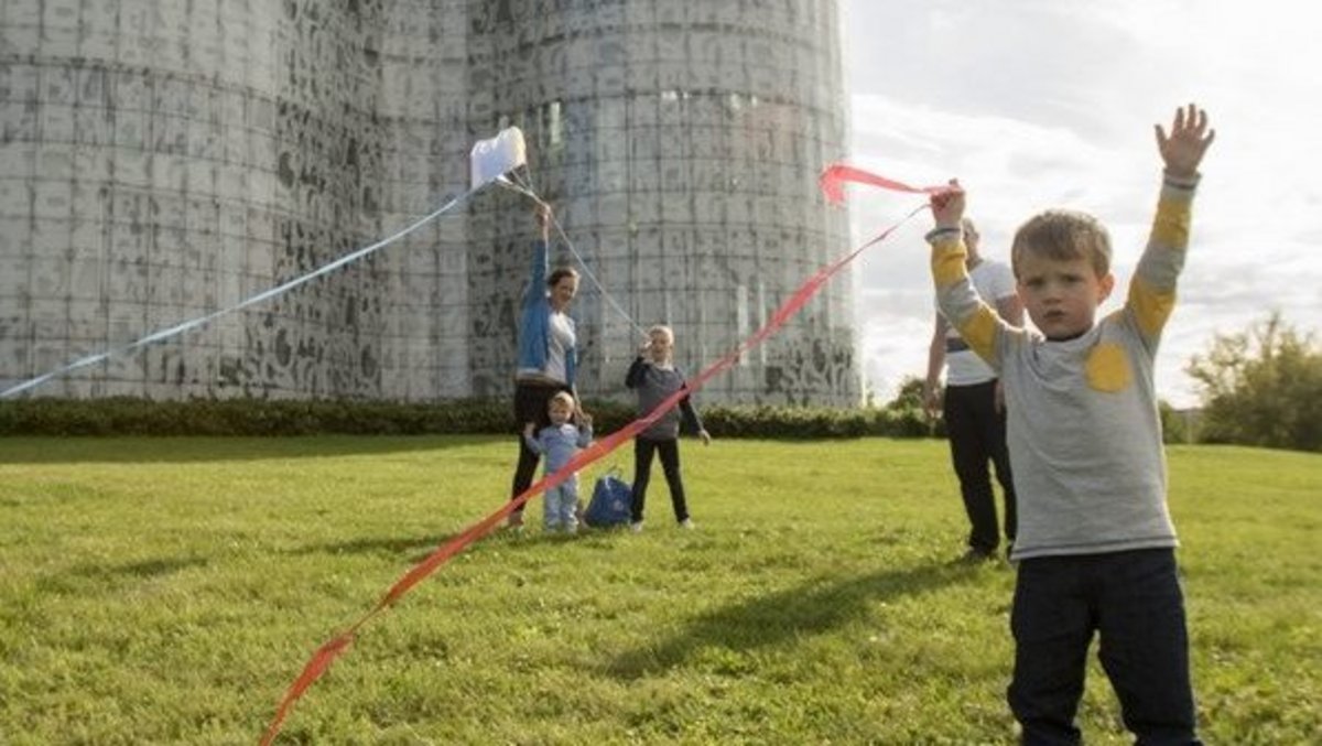 [Translate to Englisch:] Familie Spielt mit Drachen auf der Wiese vor dem IKMZ