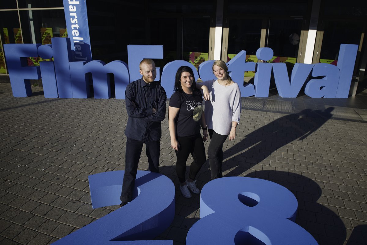 Drei BTU-Studierende stehen vor dem Schriftzug des Filmfestivals vor der Cottbuser Stadthalle
