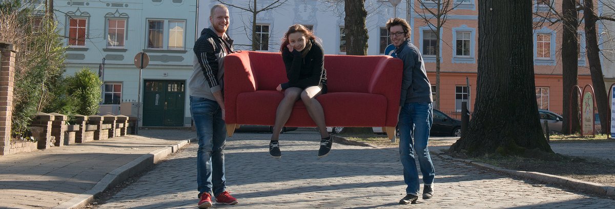 Studierende beim Umzug in der Cottbuser Altstadt Zwei Studenten tragen eine Studentin auf einem Sofa durch die Cottbuser Altstadt