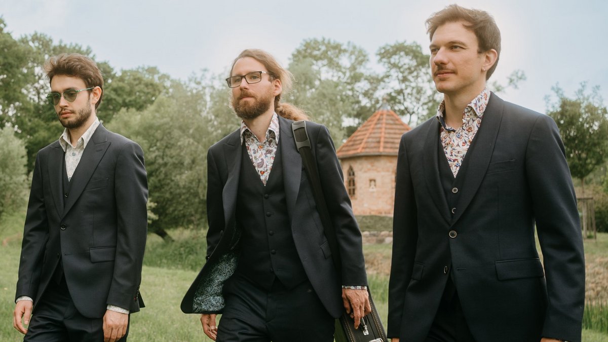 The members of the ensemble are walking through a park