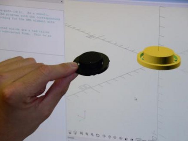 Hand hält physisches Bauteil vor Bildschirm, auf dem die digitale Version angezeigt wird