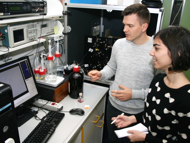 „Green Talents“–Preisträgerin Emily Elhacham aus Israel mit dem Doktoranden Vitali Scherbahn in der Biotechnologie an der BTU in Senftenberg sten am Analysegerät NANODETECTOR. Vitali Scherbahn gibt Erläuterungen.