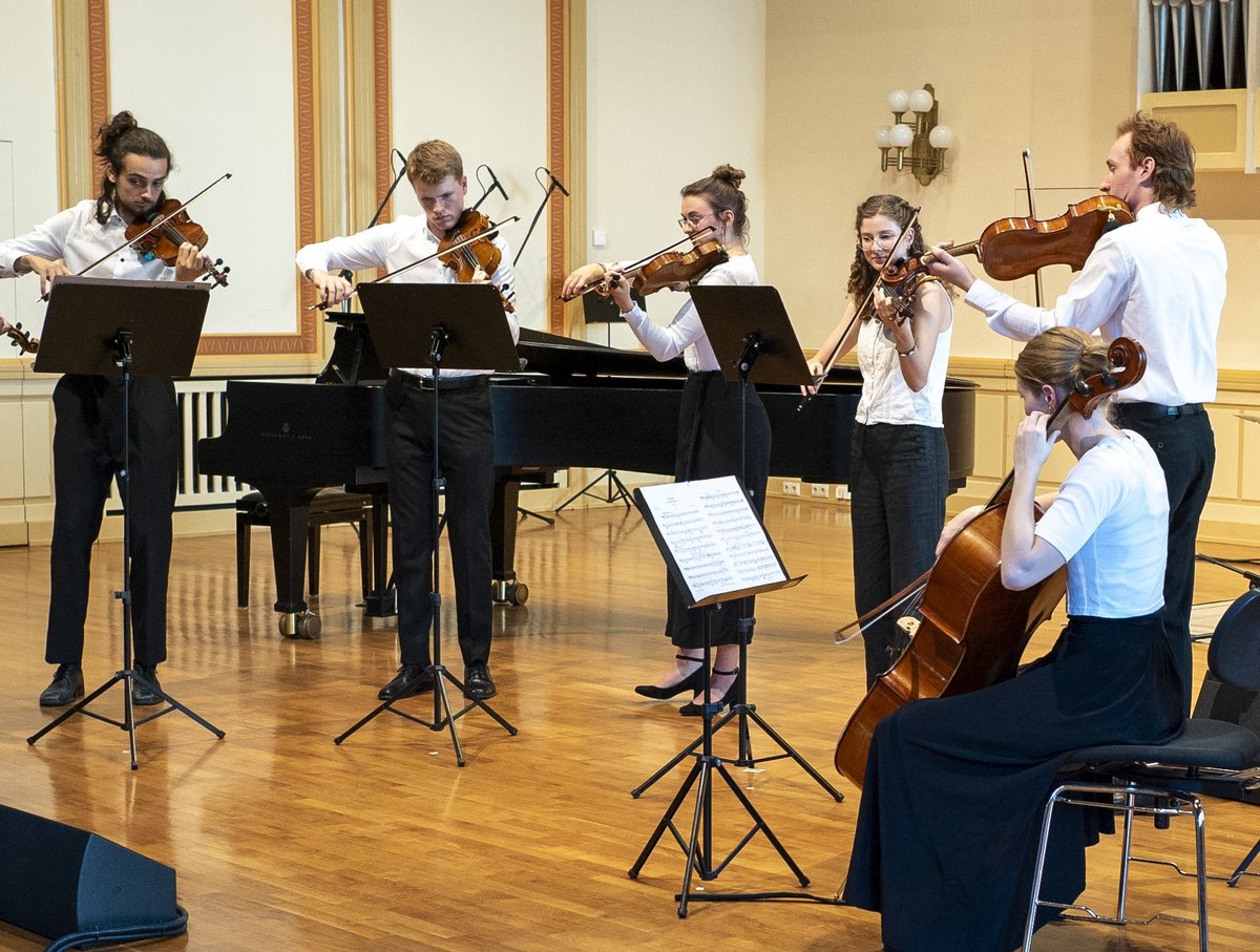 Studierende musizieren mit Streichinstrumenten.