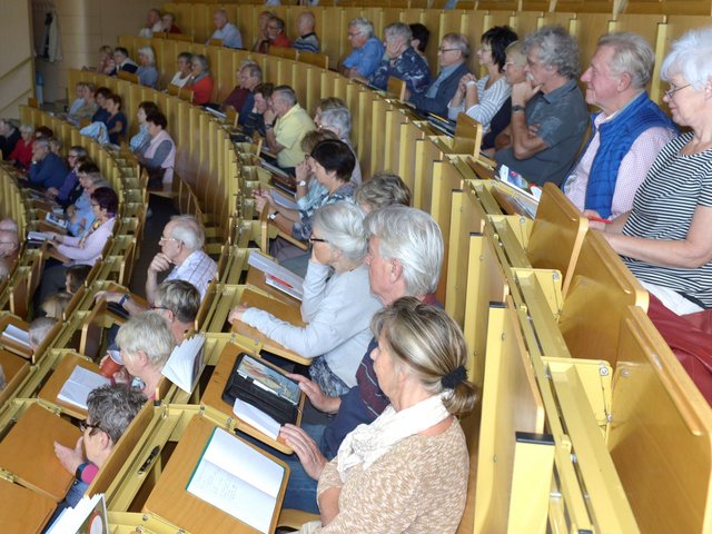 Senioren folgen, im Hörsaal sitzend, einer Vorlesung.