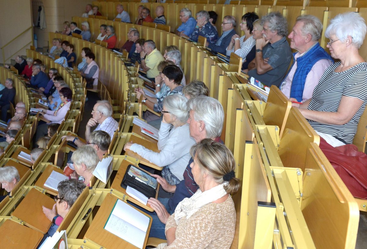 Senioren folgen, im Hörsaal sitzend, einer Vorlesung.