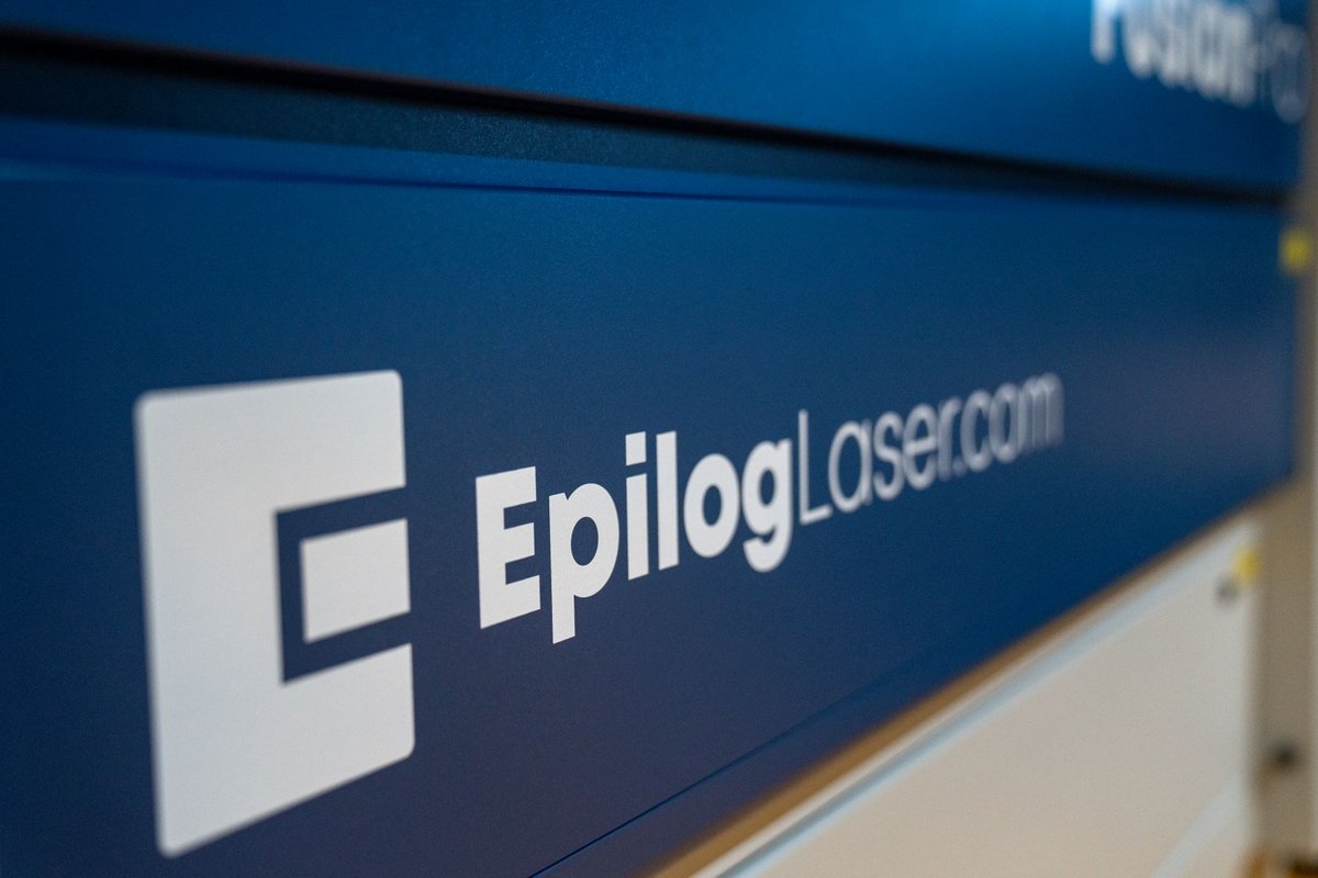 Dies ist ein weißes Logo der Firma "Epilog" auf ihrem blauen Lasercutter.