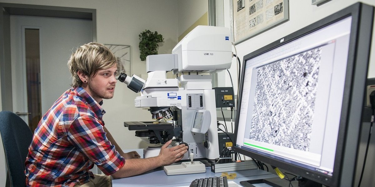 Student examines material sample under the microscope