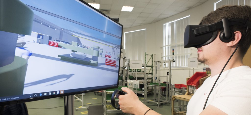 Student im Master Wirtschaftsingenieurwesen schaut sich mit VR-Brille im digitalen Modell einer Fabrik um
