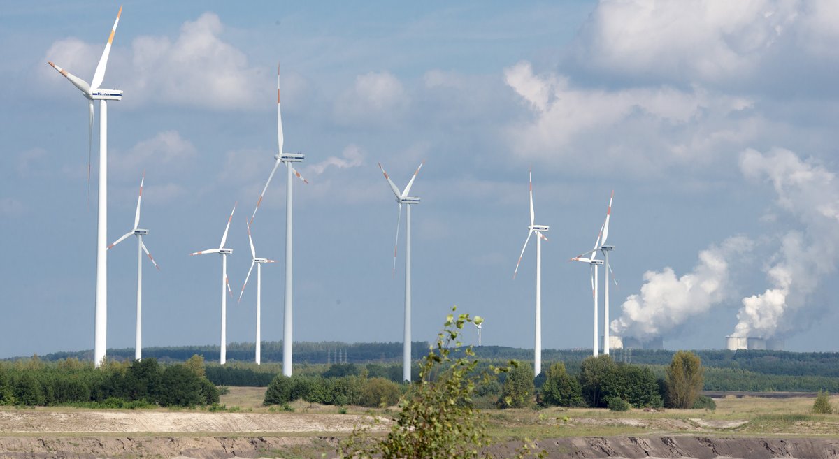 Windräder am Rand des Tagebaus mit Kohlekraftwerk im Hintergrund: Reallabor für das Studium der Energiewende