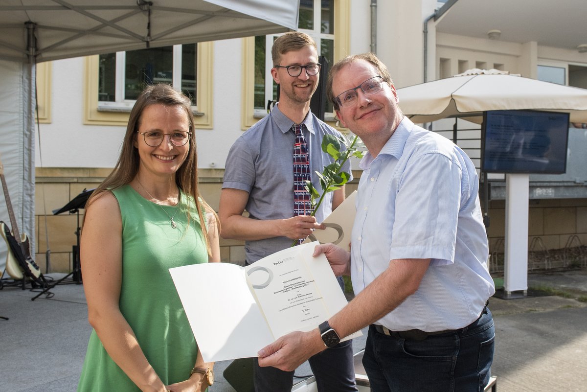 Prof. Michael Hübner mit der Urkunde für die beste Dissertation und den beiden besten Promovend*innen