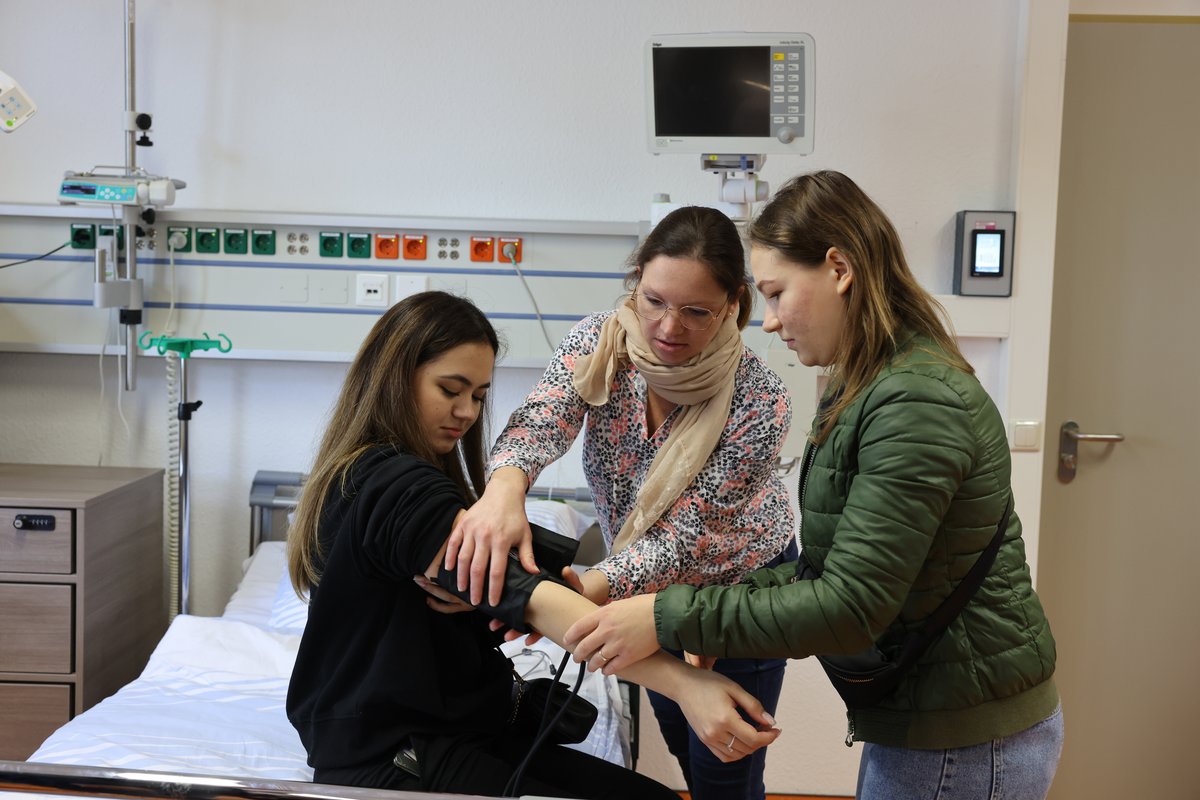 Zwei Studieninteressentinnen messen unter Anleitung einer Mitarbeiterin den Blutdruck. Foto: Steffen Rasche