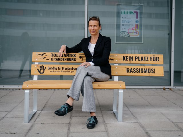Die Präsidentin sitzt auf der Bank vor dem ZHG