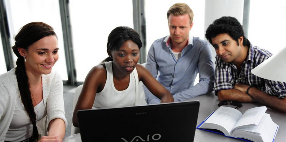 Studierende aus unterschiedlichen Nationen sitzen vor einem Laptop