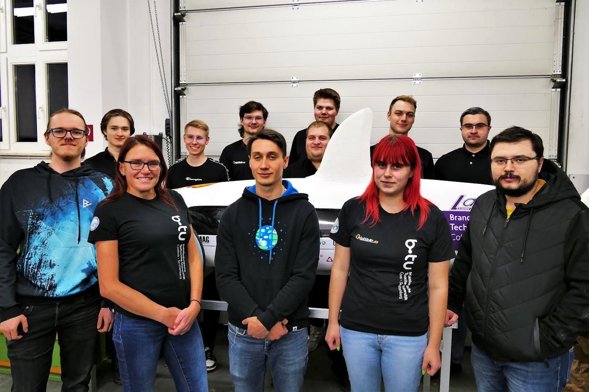 The current Lausitz Dynamics team, standing in front of and behind their vehicle.