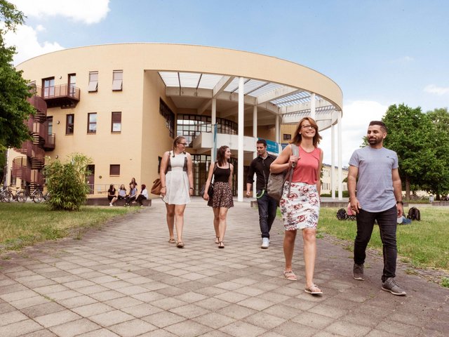 Studierende verlassen das Konrad-Zuse-Medienzentrum und laufen über den Campus.