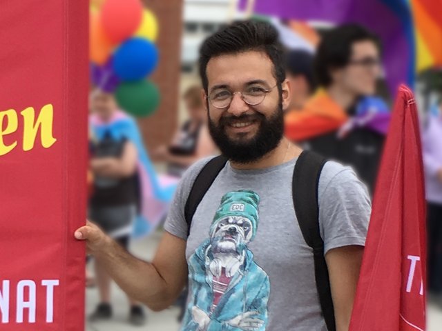 Himmat Aljasem beim CSD 2018 in Cottbus, ein Banner und eine Fahne haltend. Foto: Stefan Fiedler