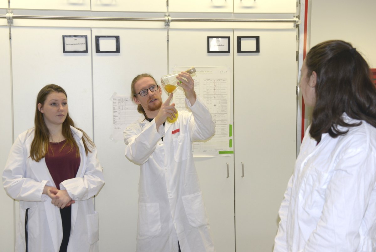 Zwei Studierende geben, im Labor stehend, eine Einführung in die Experimente.