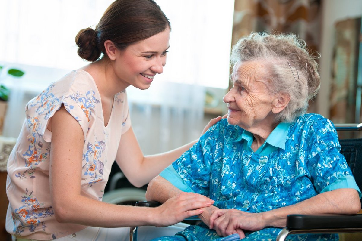 Eine ältere Patientin im Gespräch mit einer Pflegerino