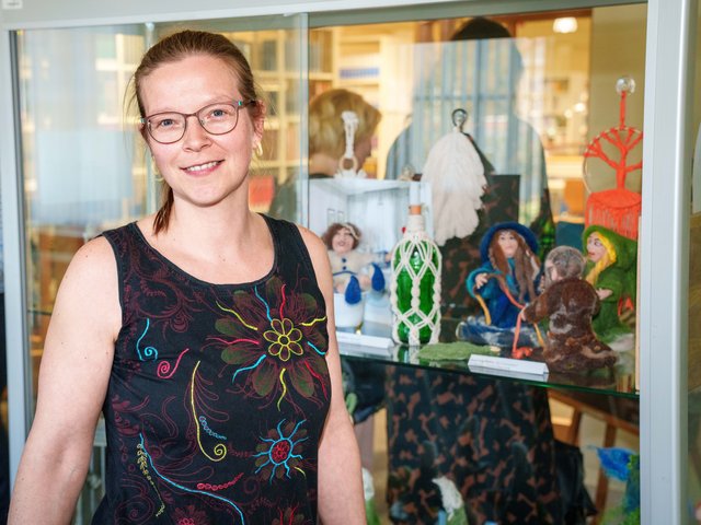 Die Bibliotheksmitarbeiterin Romy Linge-Bielert vor einer Vitrine mit einigen ihrer ausgestellten Arbeiten aus Filz.