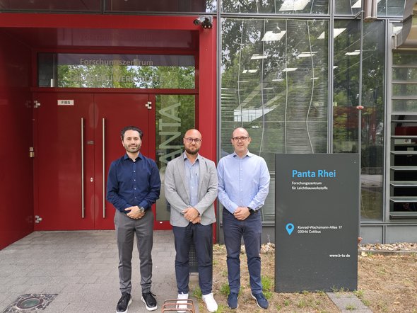 Gruppenbild mit Prof. Mattia Merlin, Prof. Sebastian Härtel und Dr.-Ing. Aliakbar Emdadi vor dem Panta Rhei Gebäude