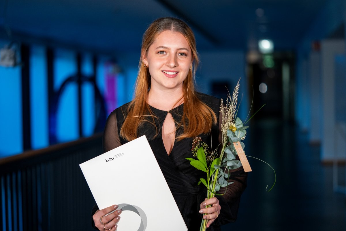Die MINT-Preisträgerin der BTU Marie Elaine Müller mit ihrer Urkunde und einer Blume.