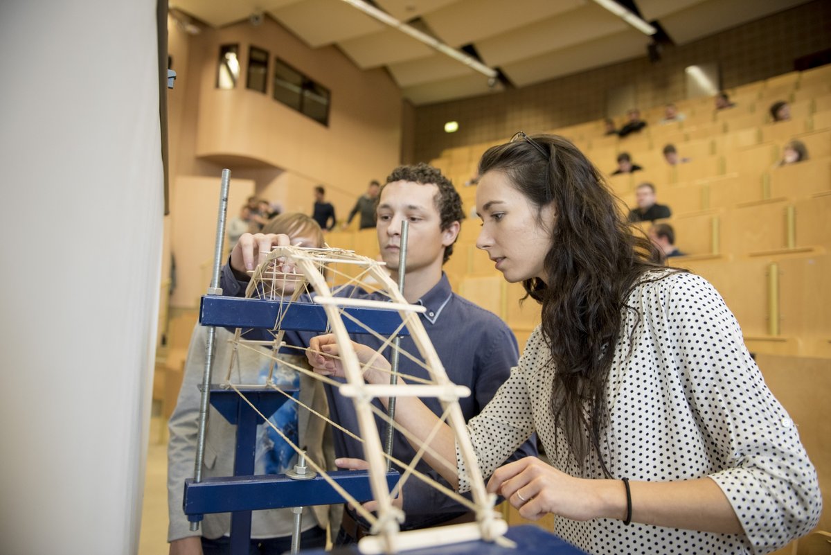 Studierende bereiten ihre Brücke auf dem Prüfstand vor, wo sie gebrochen wird.