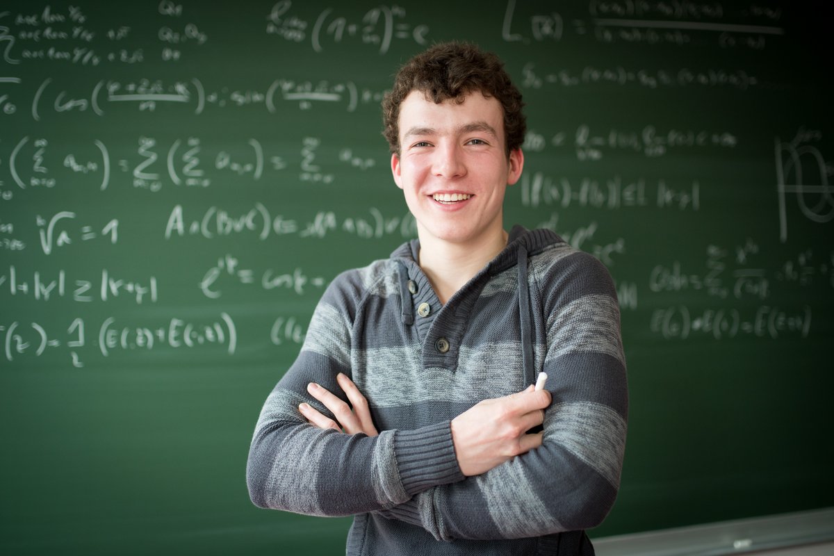 Mathematik-Student steht vor einer Tafel mit Formeln