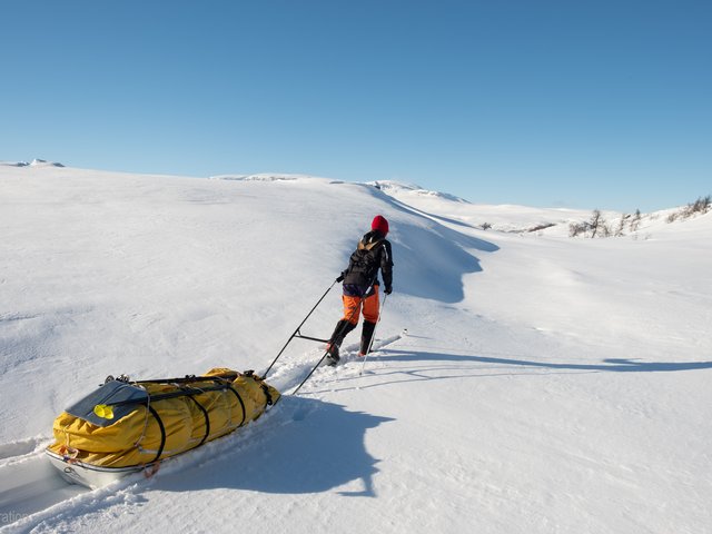 Frau zieht Schlitten durch den Schnee