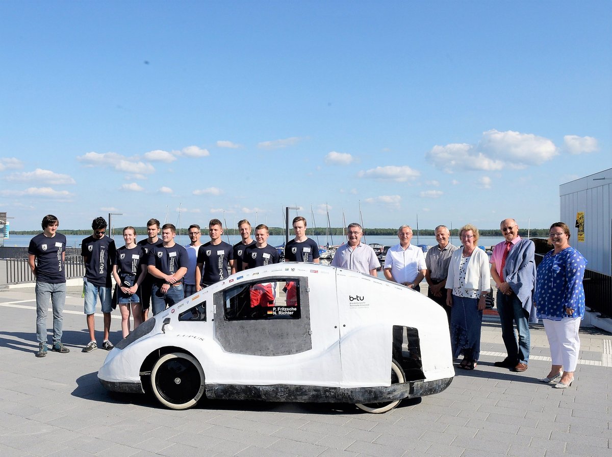 Gruppenfoto des studentischen Teams Lausitz Dynamics mit einigen seiner Unterstützer und seinem Energiesparmobil "Lupus" - aufgenommen an Senftenberger Stadthafen.