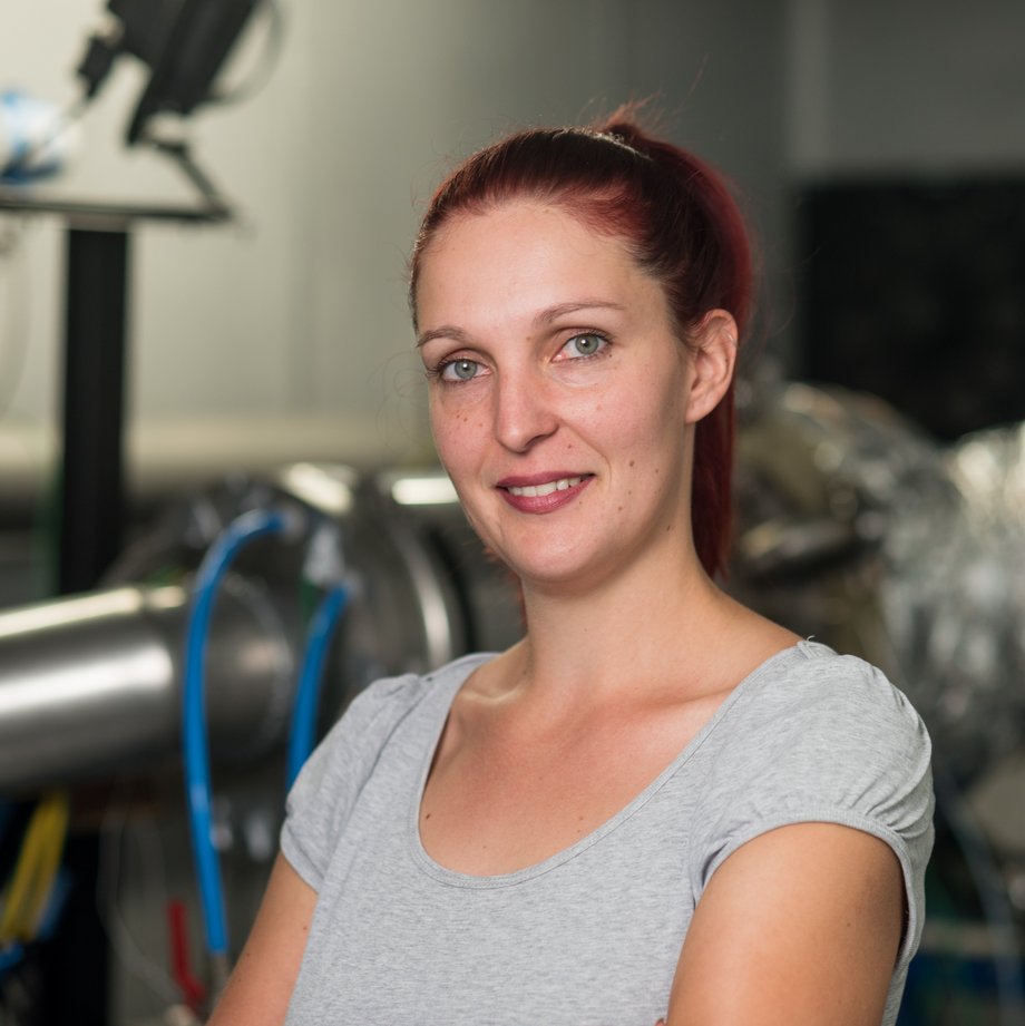 BTU-Absolventin Peggy Winkler arbeitet heute bei B+K, wo sie sich hauptsächlich mit Konstruktionsaufgaben beschäftigt. Portraitfoto von Peggy Winkler vor der Mikrogasturbine der Firma B + K