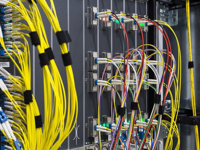 Blick in einen Rechnerschrank auf verschiedenfarbige Kabel