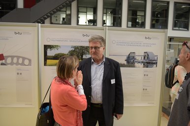 Zwei Teilnehmer des BTUTransferTages sind im Gespräch und stehen dabei vor einer Wand mit Posterpräsentationen.