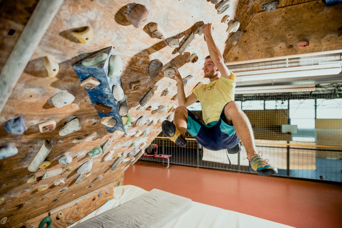 Martin Henning hängt an der Boulderwand. Er hält sich mit beiden Händen fest.